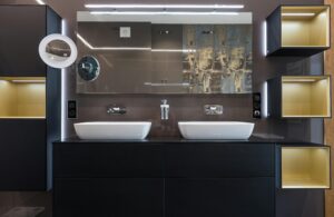 Modern interior of bathroom with double vanity with mirror and chrome faucets near illuminated shelves